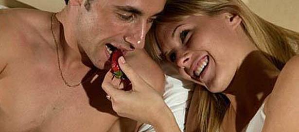 Couple eating strawberries in bed