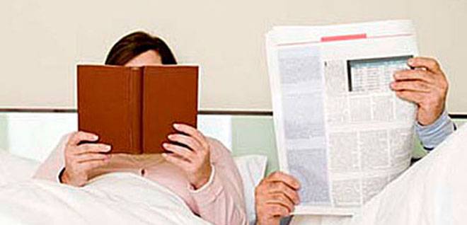 Couple reading newspaper and book