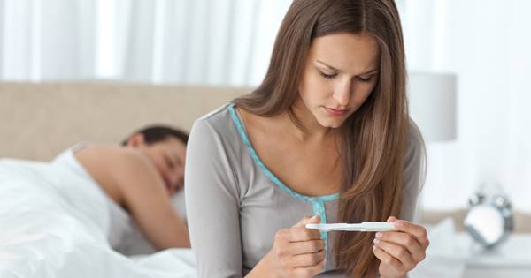 Pretty Woman Looking A Pregnancy Test While Her Boyfriend Sleepi
