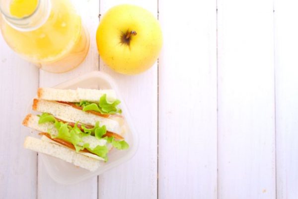 lunchbox with a sandwich, an apple and a bottle of juice for a snack