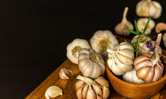 Garlic Cloves and Bulb in vintage wooden bowl.  Healthy food. Garlic on a wooden background. Traditional spices.