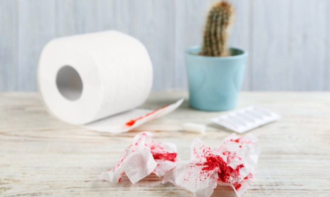 Sheets of toilet paper with blood on white wooden table. Hemorrhoid problems