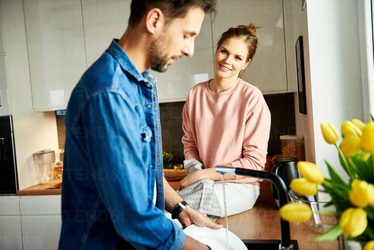 Couple talking and washing up in kitchen