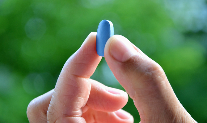 Hand,Of,Man,Holding,Blue,Pill.,Closeup,Of,A,Young