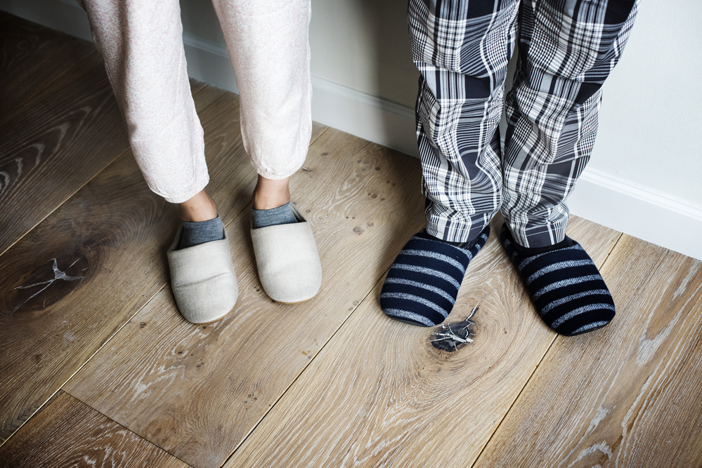 Closeup of couple wearing slippers on wooden floor