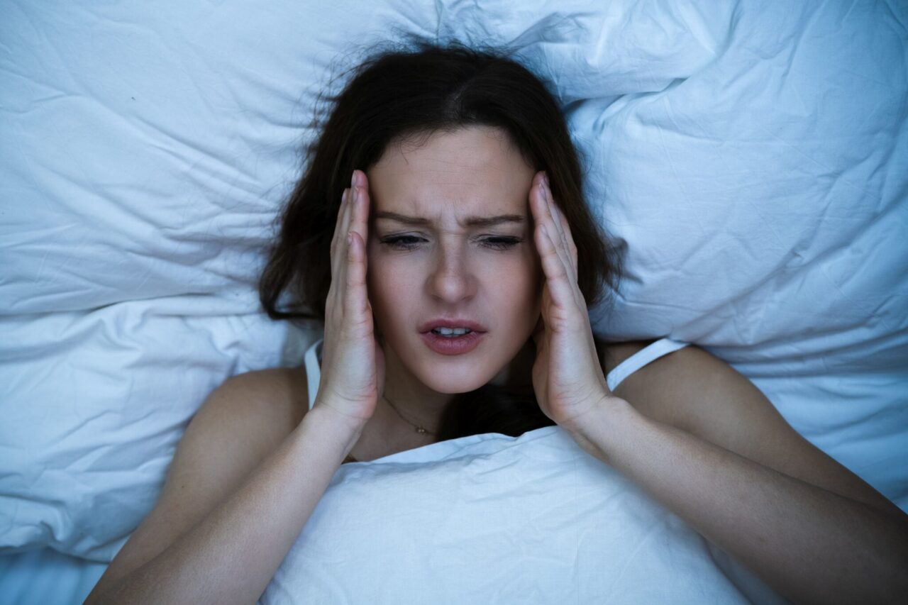 Stressed Woman With Headache Sleeping In Bed