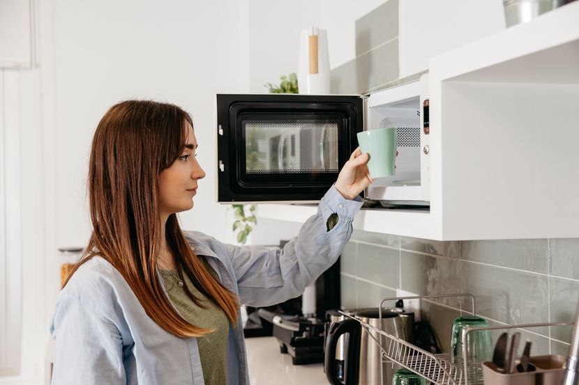 casual-girl-using-microwave-to-heat-cup-830x0