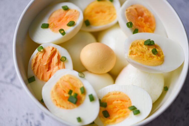 Eggs breakfast, fresh eggs menu food boiled eggs in a bowl decorated with leaves chopped fresh green onions, cut in half egg yolks for cooking healthy