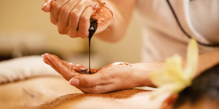 752591_closeup-massage-therapist-pouring-hot-chocolate-her-hands-before-spa-treatment_m