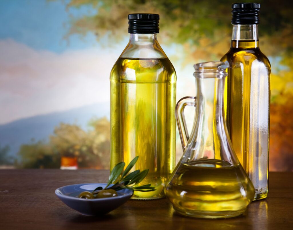 Glass bottle of premium virgin olive oil and some olives with leaves