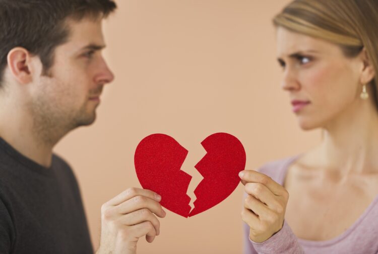 Couple holding red broken paper heart