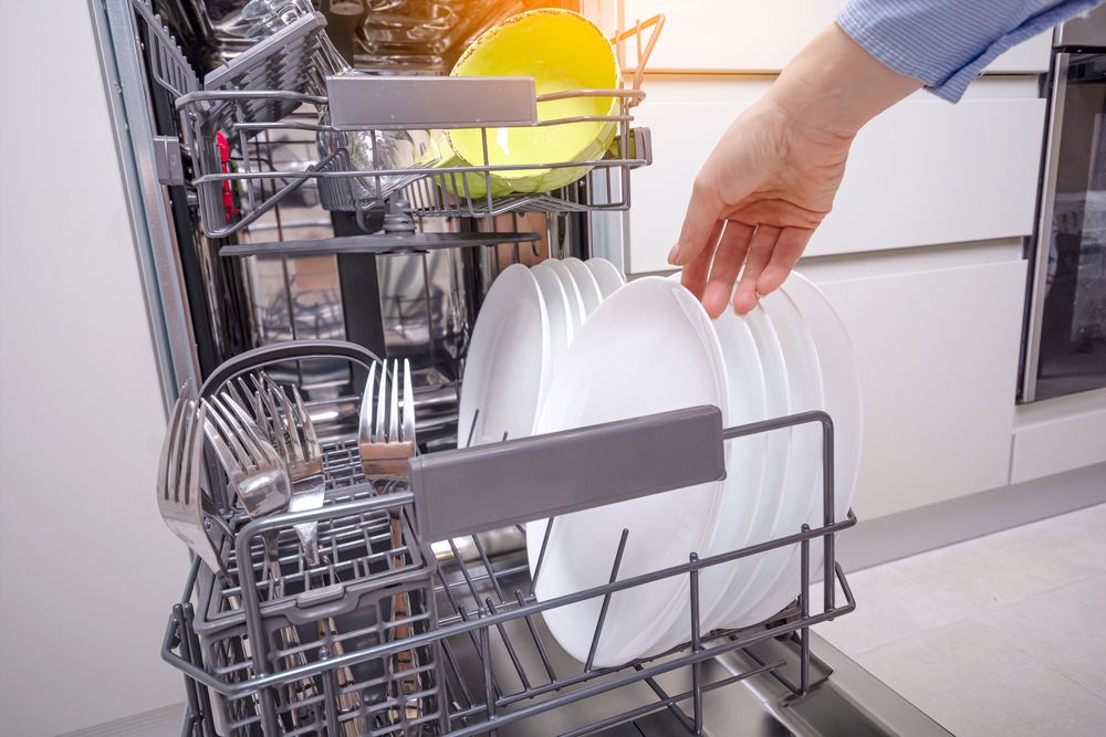 Woman,Hand,Putting,Plate,Into,Dishwasher,Machine