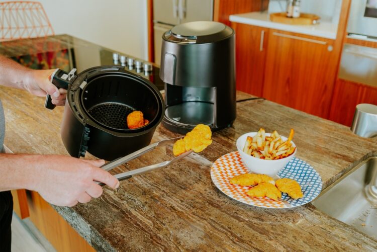 A,Person,Serves,Fries,From,An,Air,Fryer,Onto,A
